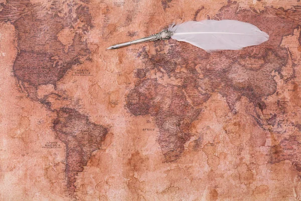 Vue du dessus de la plume avec plume blanche sur la carte du monde antique — Photo de stock