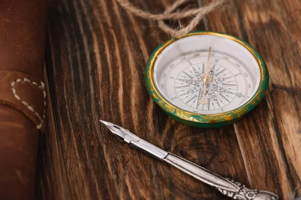 Close up view of compass near nib on brown wooden surface — Stock Photo