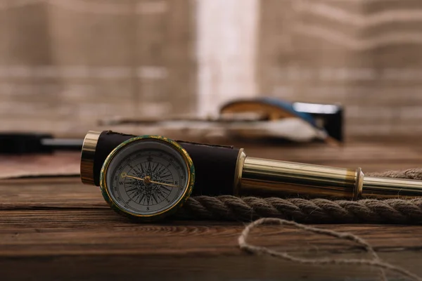 Brújula cerca del telescopio y cable de cuerda en mesa de madera marrón - foto de stock