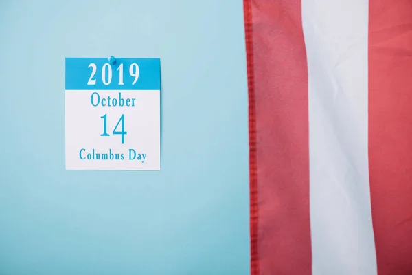 Papierkalender mit Kolumbus-Tagesinschrift in der Nähe eines Teils der amerikanischen Nationalflagge auf blauem Hintergrund — Stockfoto