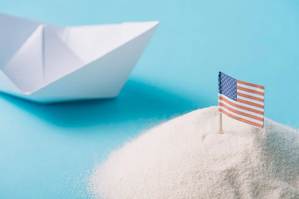 Bateau en papier blanc près du sable avec drapeau national américain sur fond bleu — Photo de stock