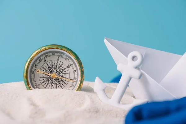 White sand with paper boat, anchor and compass isolated on blue — Stock Photo