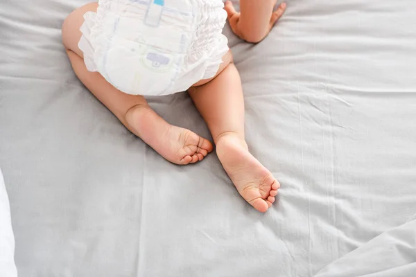 Partial view of baby in diaper crawling on white bed — Stock Photo