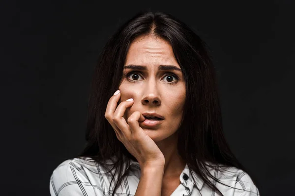 Verängstigte junge Frau berührt Gesicht isoliert auf schwarz — Stockfoto