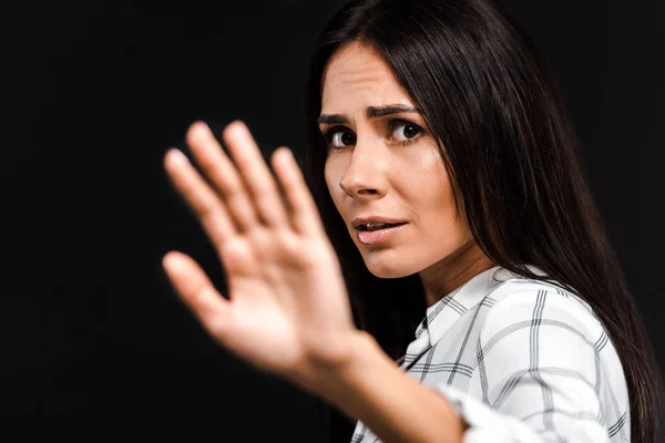 Selective focus of upset woman gesturing while looking at camera isolated on black — Stock Photo