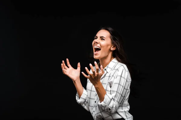 Mujer emocional gritando y haciendo gestos aislados en negro - foto de stock