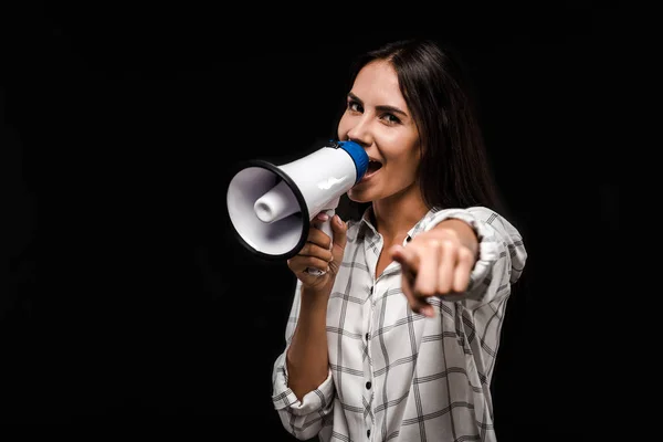 Selective focus of happy woman holding megaphone and pointing with finger isolated on black — Stock Photo