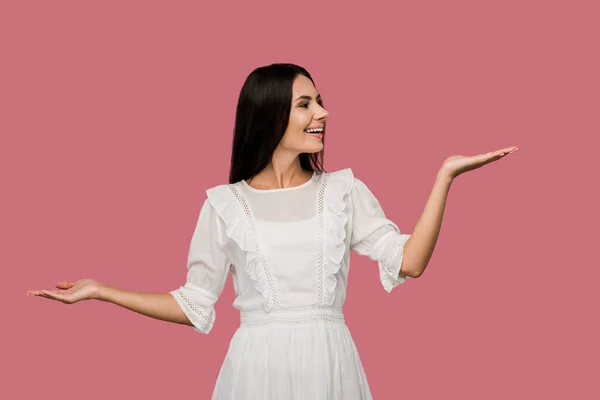 Весела жінка в білій сукні жестикулює ізольовано на рожевому — стокове фото