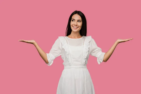Jovem alegre em vestido branco gesticulando isolado em rosa — Fotografia de Stock