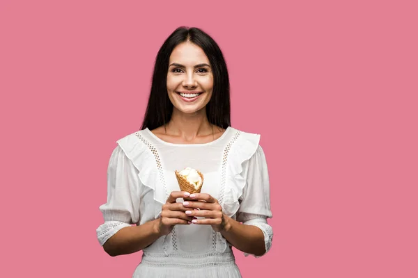 Cheerful woman in dress holding tasty ice cream cone isolated on pink — Stock Photo