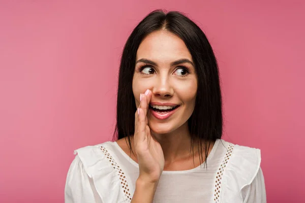 Felice donna toccare il viso mentre spettegola isolato su rosa — Foto stock