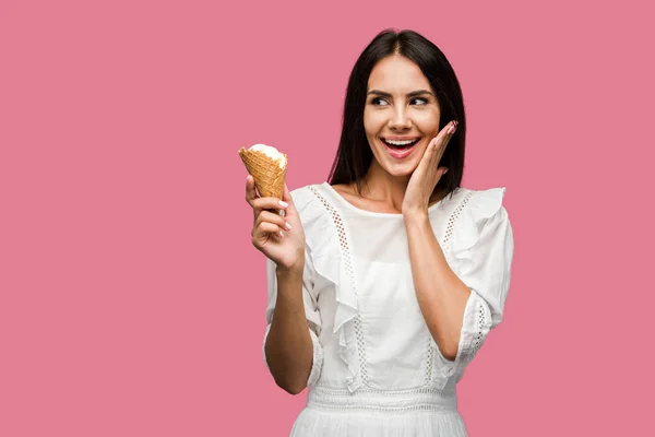 Excited woman in dress holding tasty ice cream cone isolated on pink — Stock Photo