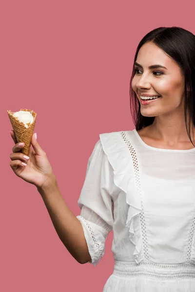 Cheerful young woman in dress looking at tasty ice cream isolated on pink — Stock Photo