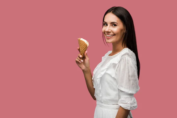 Fille gaie en robe tenant cône de crème glacée isolé sur rose — Photo de stock