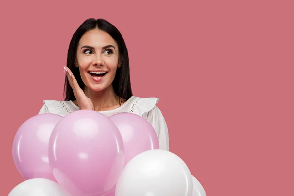 Mujer excitada sosteniendo globos aislados en rosa — Stock Photo