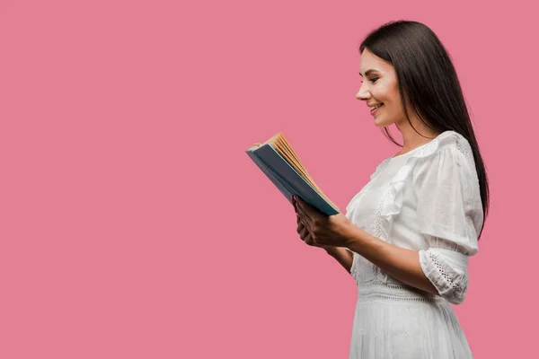 Весела жінка в сукні читає книгу ізольована на рожевому — стокове фото