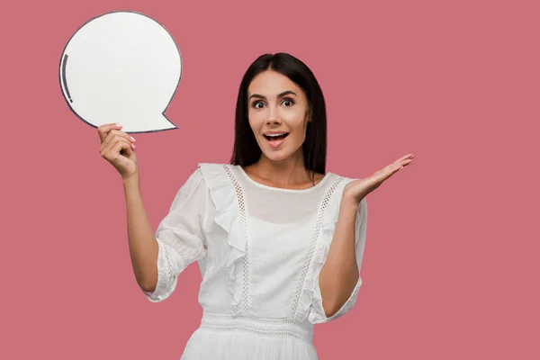 Surprised young woman holding blank speech bubble and gesturing isolated on pink — Stock Photo