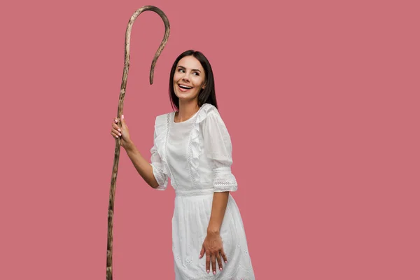 Smiling woman holding wooden cane isolated on pink — Stock Photo