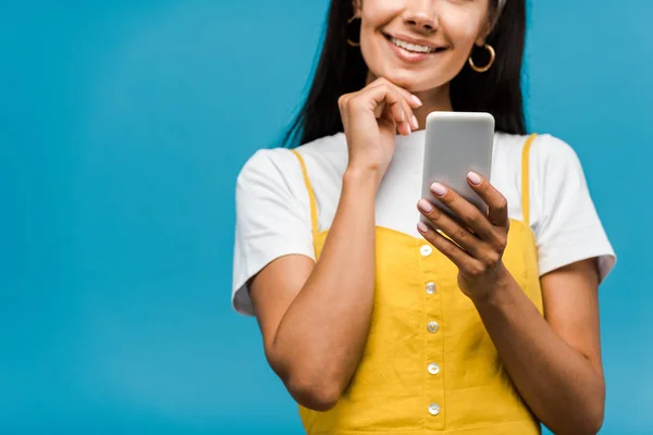Vista recortada de la mujer feliz sosteniendo teléfono inteligente aislado en azul - foto de stock