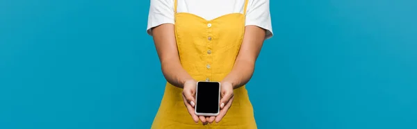 Панорамний знімок жінки, що тримає смартфон з порожнім екраном ізольовано на синьому — стокове фото
