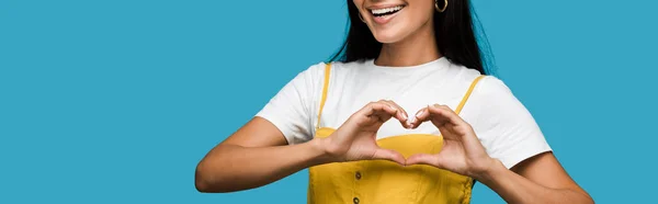 Panoramic shot of happy young woman showing heart with hands isolated on blue — Stock Photo