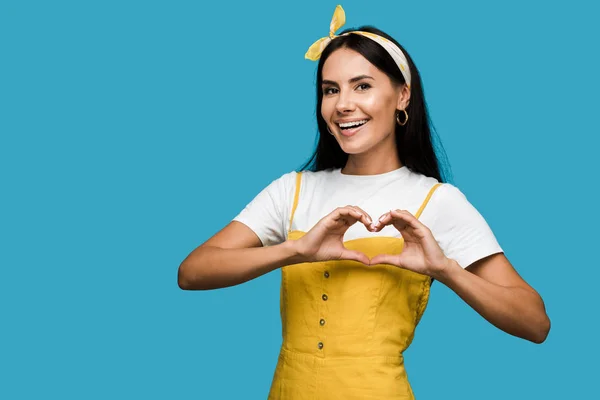 Heureuse jeune femme montrant coeur avec les mains isolées sur bleu — Photo de stock