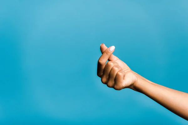 Vista recortada de la mujer joven mostrando el corazón con la mano aislada en azul - foto de stock