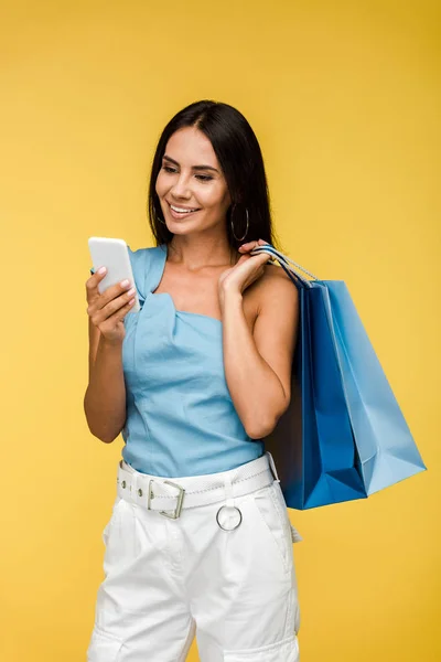 Alegre joven mujer mirando teléfono inteligente aislado en naranja - foto de stock