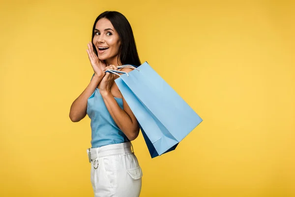 Mujer excitada sosteniendo bolsas aisladas en naranja - foto de stock