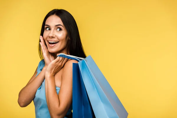 Aufgeregte junge Frau mit Einkaufstaschen in Orange — Stockfoto