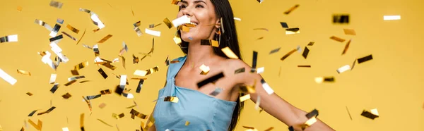 Panoramic shot of cheerful woman near sparkling confetti on orange — Stock Photo