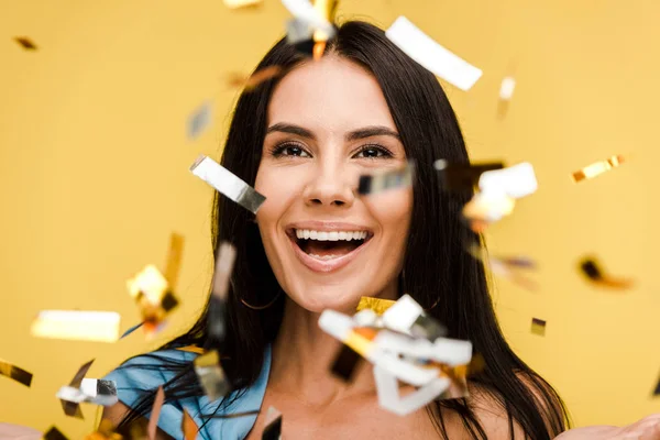 Foyer sélectif de femme heureuse près de confettis étincelants sur orange — Photo de stock