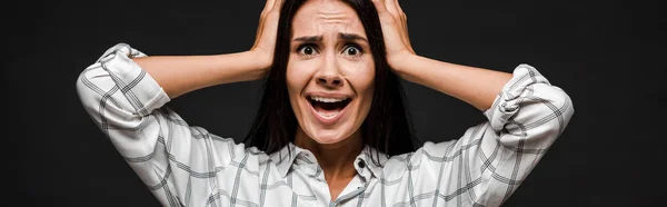 Panoramic shot of scared woman holding head isolated on black — Stock Photo
