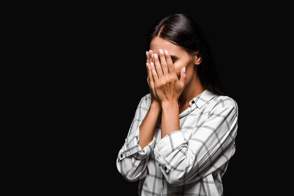 Засмучена жінка закриває обличчя ізольовано на чорному — стокове фото