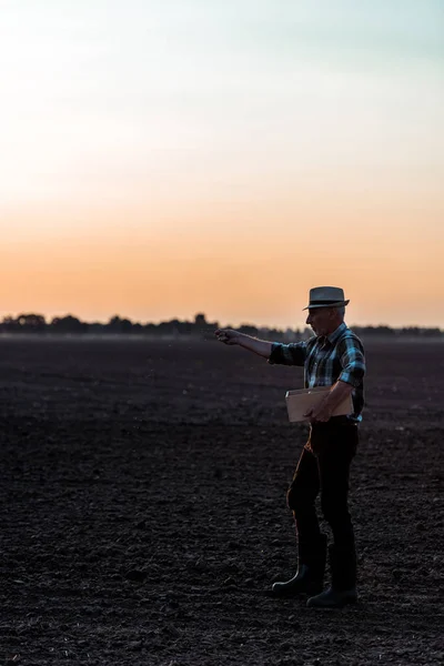 Profile of self-employed man in straw hat standing and sowing seeds — Stock Photo