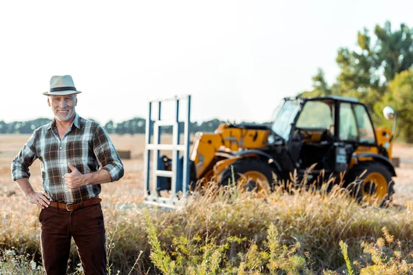 Happy senior farmer showing thumb up near tractor — Stock Photo