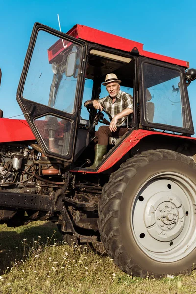 Agricultor autónomo senior en sombrero de paja tractor de conducción - foto de stock