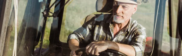 Panoramic shot of self-employed farmer in straw hat driving tractor — Stock Photo