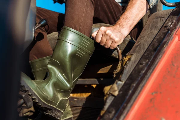 Cropped view of senior farmer driving tractor — Stock Photo