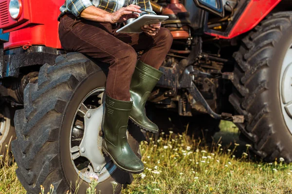 Vue recadrée d'un agriculteur utilisant une tablette numérique près d'un tracteur rouge — Photo de stock