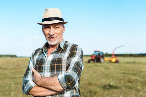 Agricultor sênior feliz de pé com braços cruzados no campo — Fotografia de Stock