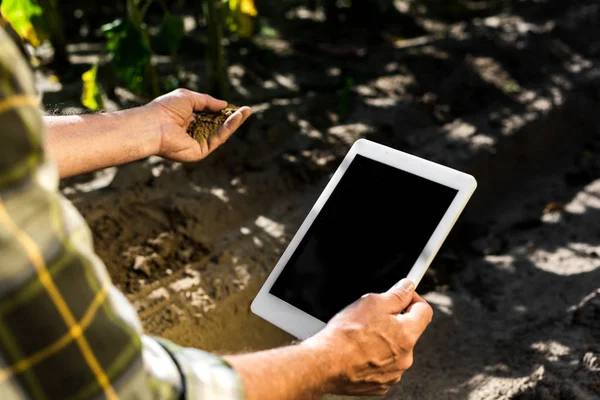 Vista recortada del agricultor autónomo senior que sostiene una tableta digital con pantalla en blanco - foto de stock