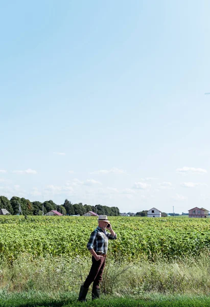 Самозайнятий фермер розмовляє на смартфоні, стоячи з рукою на стегні — стокове фото