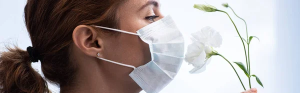 Panoramic shot of woman in medical mask smelling flowers — Stock Photo