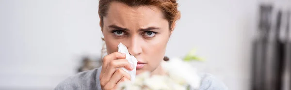 Panoramaaufnahme einer kranken Frau mit Pollenallergie, die Gewebe in der Nähe von Blumen hält — Stockfoto