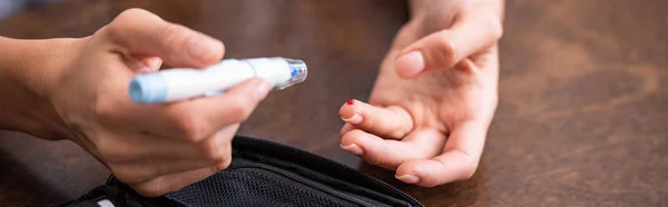 Tiro panorâmico de mulher segurando lanceta de sangue perto do dedo com sangue — Fotografia de Stock