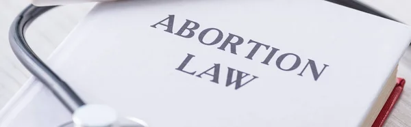 Panoramic shot of book with abortion law lettering near stethoscope — Stock Photo