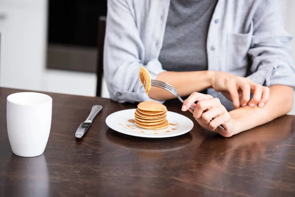 Cropped view of woman scratching hand near sweet pancakes on plate — Stock Photo