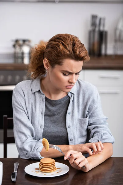 Donna sconvolta graffiare mano vicino dolci frittelle sul piatto — Foto stock