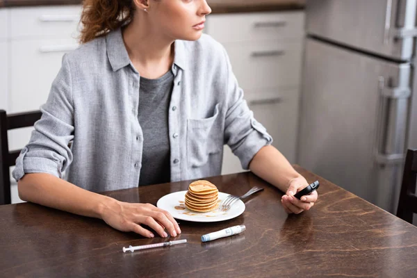 Vue recadrée de la femme diabétique tenant un glucomètre près des crêpes — Photo de stock